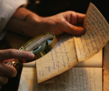 hand holding magnifying glass to written letter