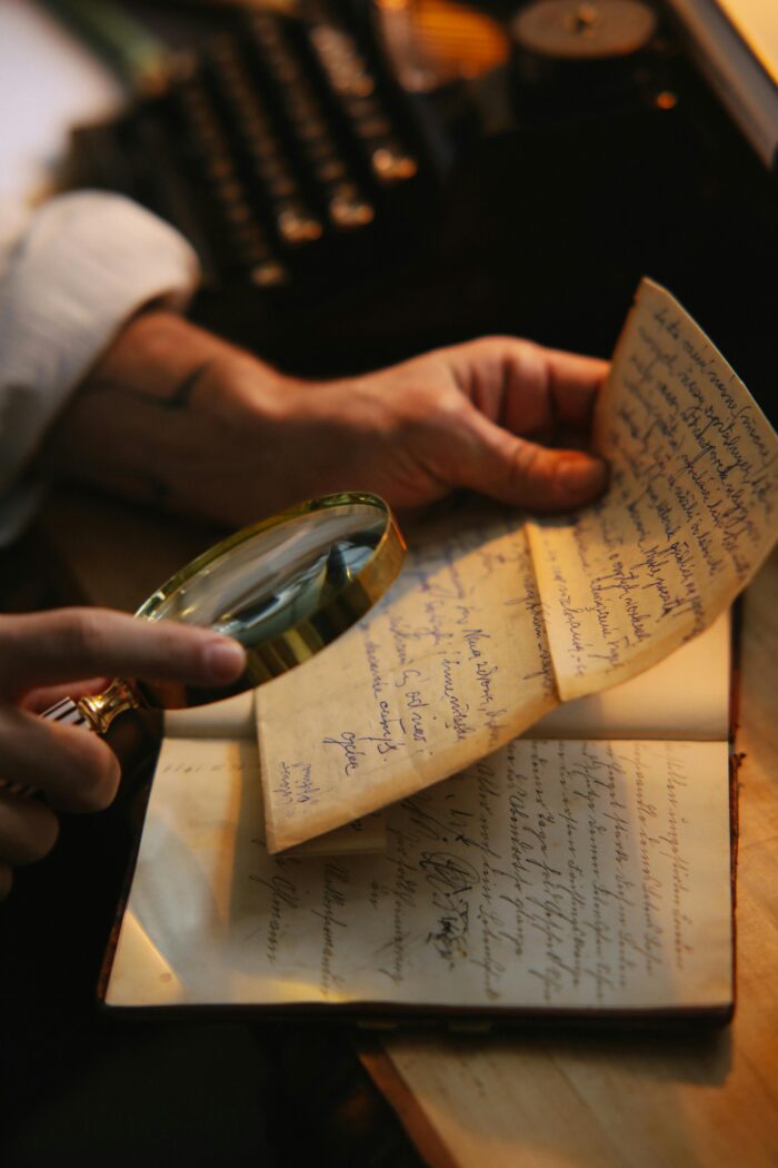 hand holding magnifying glass to written letter